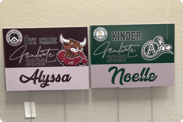 Yard signs for graduates with grade, year, school logo, and graduate name
